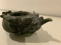 Side profile showing carved dragon head detail on jade incense/candle holder.