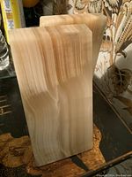 Front and angled view of one marble bookend showing natural cream and beige striations and smooth finish.