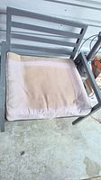 Outdoor wide seat chair with light beige fabric cushion showing discolouration and stains