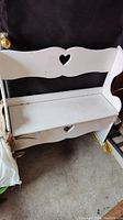Front view of white wooden bench with heart-shaped cutout on backrest