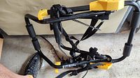 Single car bike rack with black metal frame, yellow plastic parts, padded supports, and securing straps