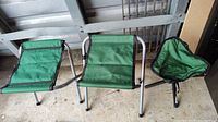 Three foldable camping stools with green fabric seats and silver metal frames, arranged side by side to show different seat shapes.