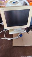 Beige Compaq CRT monitor with attached power and VGA cables, showing scratches on the screen.