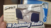 Photo showing box and unit of an INNOVAGE FM Scanning Radio player with features listed and price tag on box.