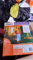 Box showing Airflowz inflatable pumpkin head scarecrow package and deflated inflatable figure inside