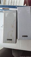 Photo showing two Nakamichi speakers with gray fabric grilles, one with visible stains.