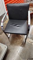 Black fabric office desk chair with silver metal frame, showing wear and scratches