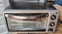 Black & Decker toaster oven from front, showing glass door, metal handle, and control knobs.
