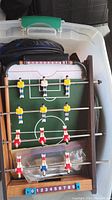 Foosball game set with rods, players in yellow, red and white, and scoreboard.