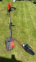 Full view of the two electric trimming tools laid on grass: Black & Decker Edge Hog with wheels and Jobmate edge trimmer with red and black body.