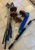 Photo showing 6 golf clubs with grips, two dumbbells with dark red weight plates, and a blue stretch bar on the floor
