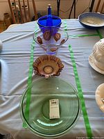 Overview of various glass bowls including clear, amber accented, and green tinted bowls along with a blue glass bottle and the brown fluted chip bowl on a table.