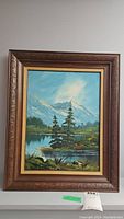 Full view of framed oil painting showing mountain landscape with lake and trees