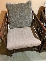 Front view of a bamboo chair showing beige seat cushion and black-and-white speckled pillow with fringed edges