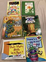 Top view of six bug-themed pop-up children's books arranged flat on a surface.