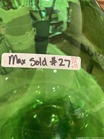 Close-up showing the green glass texture and a label with the container's dimensions.