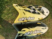 Two Ski-Doo branded toboggan sleds placed side by side on grass showing overall design and condition.
