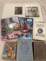 Overview of all books and photos laid out on fabric background, including the signed Willie Nelson book, Scouts Stories and Victory Cookbook, and Christmas books.