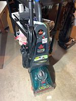 Front angle view of the Bissell ProHeat Turbo 2X carpet cleaner showing controls, branding, side mesh accessory holder, and cord.