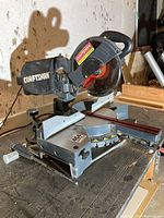 Full view of the miter saw on workbench showing base, blade, motor housing and dust bag