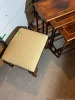 Photo showing fabric topped stool with yellow and white zigzag cushioned seat and wooden legs.