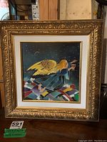 Full view of silkscreen painting in ornate wood frame depicting an angel flying over colorful hills at night.