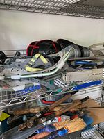 Grey and green Tubbs snowshoes stacked on shelf with toe and heel straps visible, aluminium frames, and molded traction pads. Poles and guard padding visible.