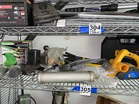 Wide view of shelf showing Kawasaki box, various automotive and mechanical parts, and hand planer.