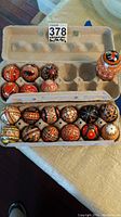 Set of 18 Ukrainian painted Easter eggs in an open egg carton showing various hand-painted traditional patterns.