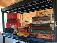 Overview of stacked vintage games and puzzles on black shelving unit.