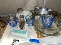 Overview photo showing vintage Pyrex butter dish, blue glasses, tall decorated glasses, pie plates, cake pan, and Fire King bowl on shelf.