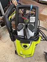 Front view of green pressure washer unit with handle, dual detergent tanks, coiled high-pressure hose and spray gun mounted