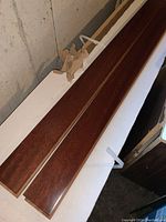 Close-up photo showing two samples of reddish-brown polished hardwood planks from the Royal Crown Collection, 3 inch wide Tatajuba Orinoco hardwood flooring.