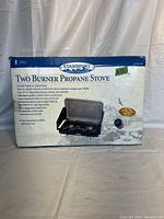Front view of the boxed Stansport two burner propane stove showing product image, features, and branding on box.