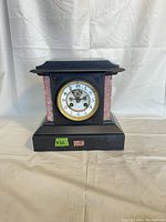 Full frontal image of the antique mantel clock showing black metal case, pink marble side columns and clock face with glass cover.