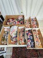 Overview of six boxes filled with vintage political campaign buttons arranged on a table showing different campaigns and slogans.
