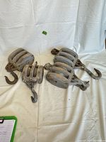 Four wooden pulleys with metal hooks arranged together against a white backdrop, showing general overview of all items.