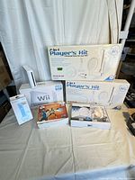 Full lot displayed showing Nintendo Wii console, two 2-in-1 Player's Kit boxes, Wii Remote Plus package, and two EA Sports Active 2 game boxes.