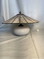 Full view of the lamp showing oval crackle glaze ceramic base with large conical stained glass shade and brass toned finial at the top.
