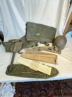 Overview photo showing all items in the lot including bags, helmet, tool, and box.