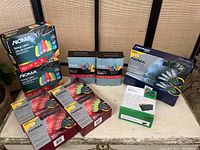 Photo showing multiple boxes of Christmas lights on a table, branded NOMA and In Style, with visible count of 11 total boxes.