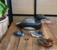 Photo showing all five ducks on wooden surface against bamboo screen background