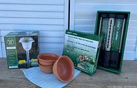 Eight Westinghouse solar lights, three terracotta clay pots, Orbit sprinkler box and components on display.