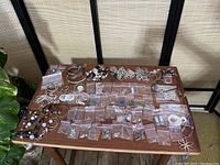 Overview of the entire jewelry lot on a wooden table with small zipper bags and loose items.