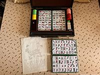 Open case showing Mahjong tiles, chips, dice, and instruction sheets laid out.