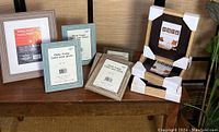 Wide view of ten assorted new photo frames in various colors and sizes displayed on wooden furniture.