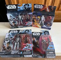 Four Star Wars action figure packages displayed on wood surface. Figures are new in package and include Captain Phasma and other Star Wars characters from The Force Awakens and Rogue One.