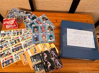Spread of vintage baseball cards, sheets, and box on wooden surface