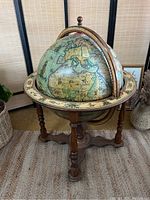 Full frontal view of the globe bar cart on tripod base