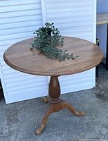 Full view of the round wooden table with plant on top to show size and shape.